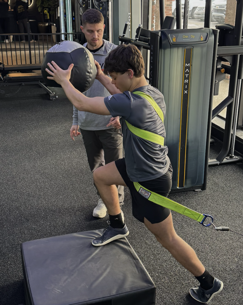 Athlete doing ACL rehab exercises with sports physical therapist in clinic